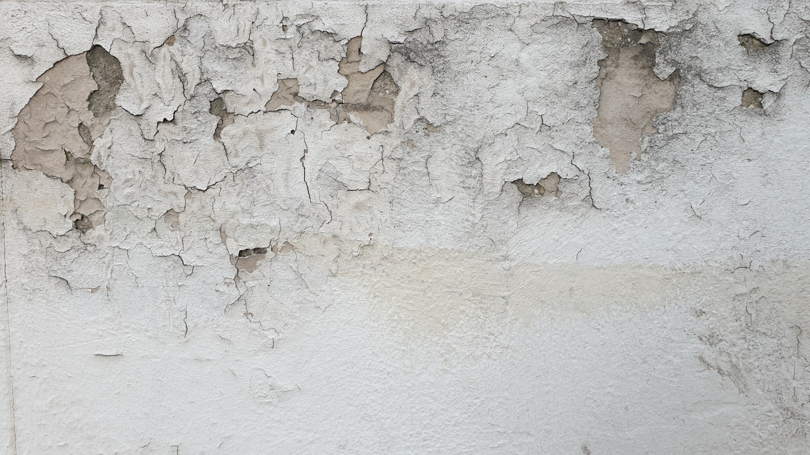 Parete con intonaco deteriorato e crepe superficiali